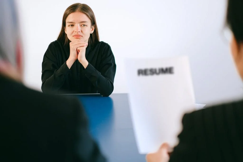 Image of man looking at a resume as he interviews a young lady.