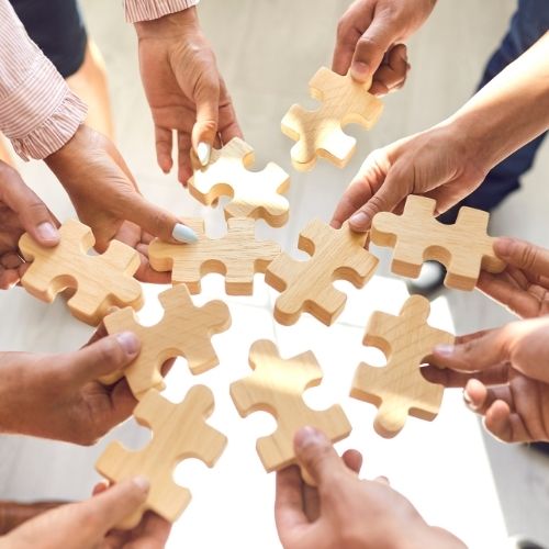 Image of a team holding puzzle pieces for team building to boost morale on your team.