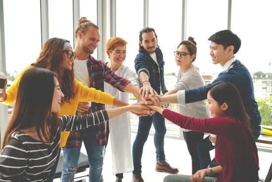 Image of co-workers putting their hands together in the middle of a circle after team building activities for work, team building games, team building exercises.