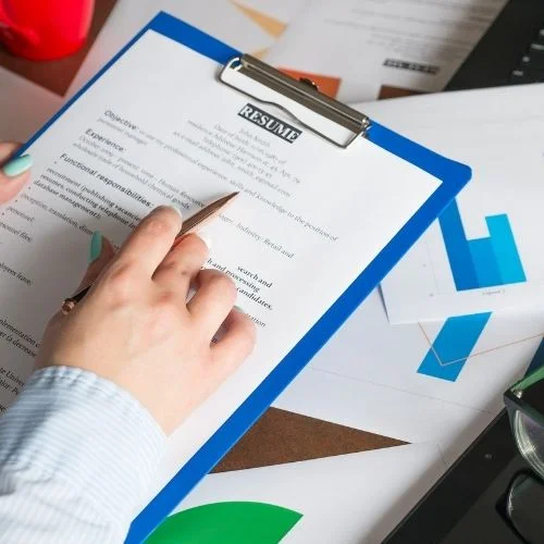 Image of a person reviewing resumes for the post-interview process. The post-interview is one of the employer interview techniques.