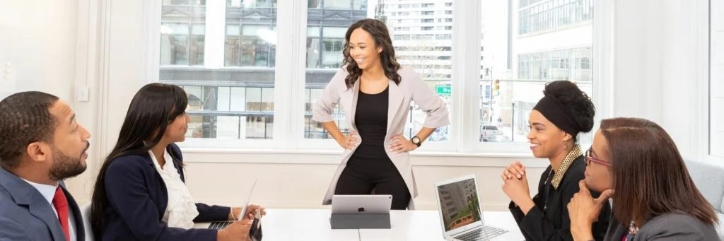 Image of employees sitting around a table having a meeting. How to handle disrespect in the workplace.