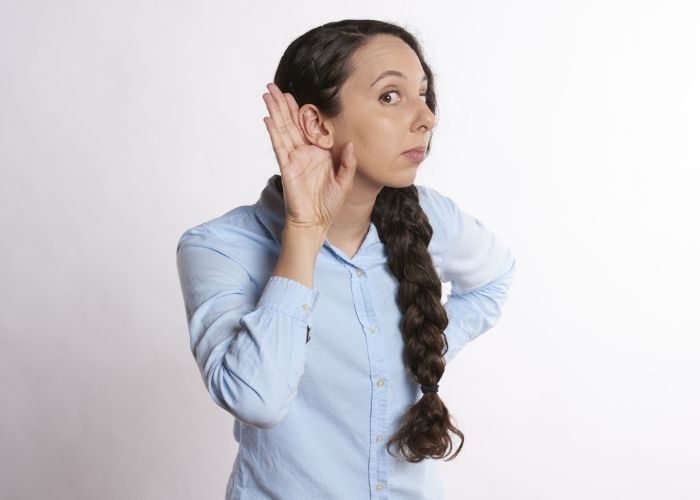 Image of a lady holding her hand to her ear for listening.