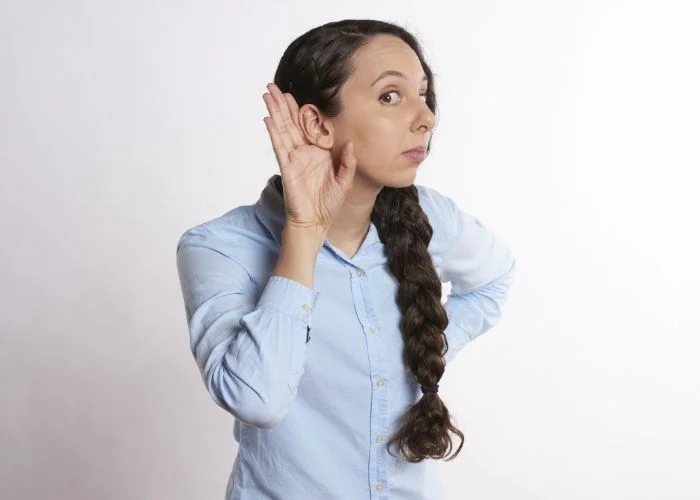 Image of a lady holding her hand to her ear for listening.