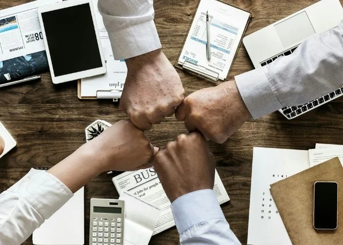 Image of employees fist-bumping to build strong work relationships.