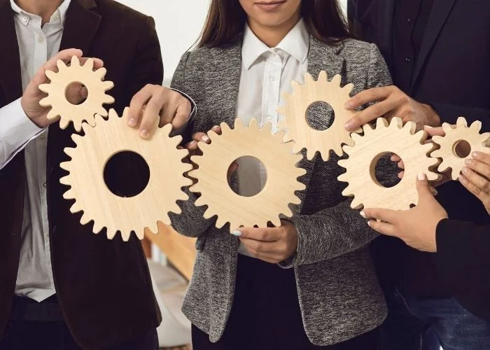 Group of employees holding gears to show why teamwork is important in the workplace.