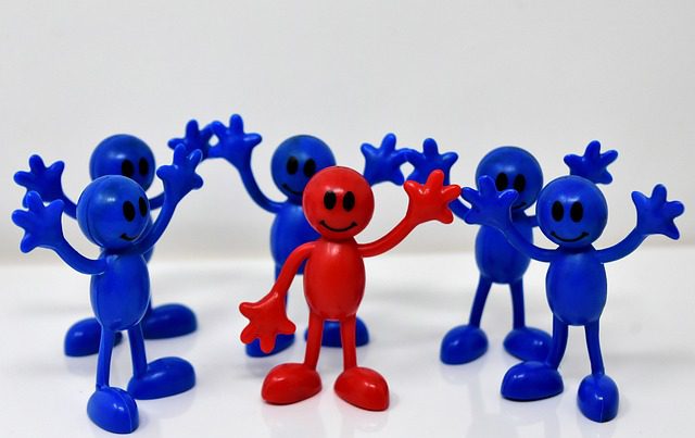 One red figure with five blue figures around him all waving empowering a happy team for ways to build trust at work.