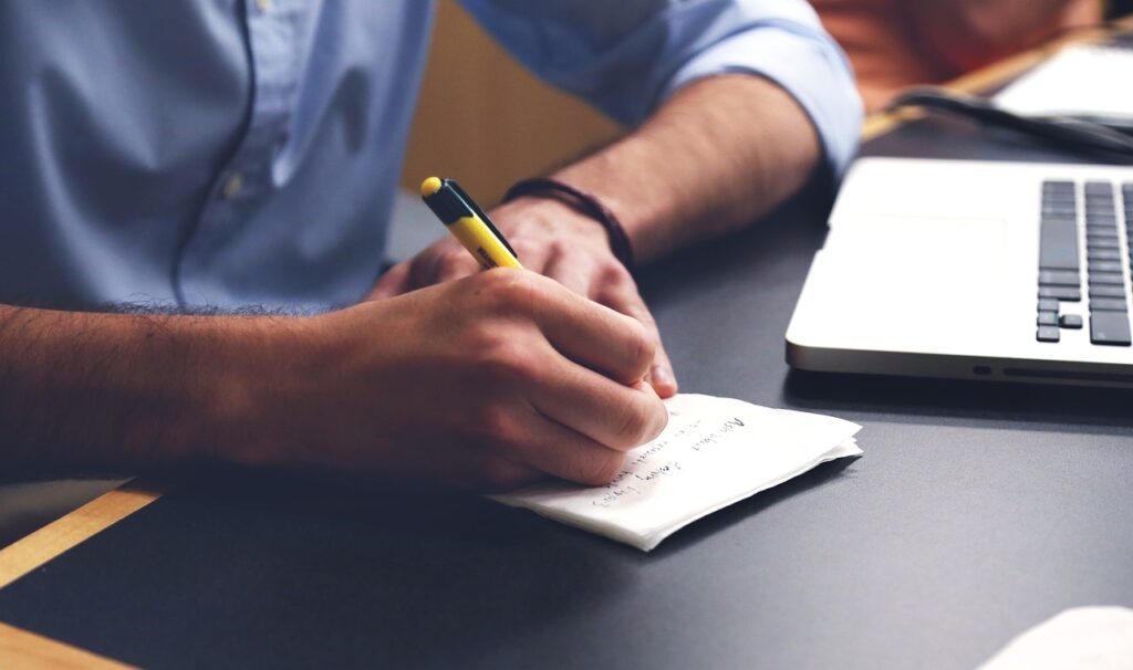 person writing showing the written type of communication in business.