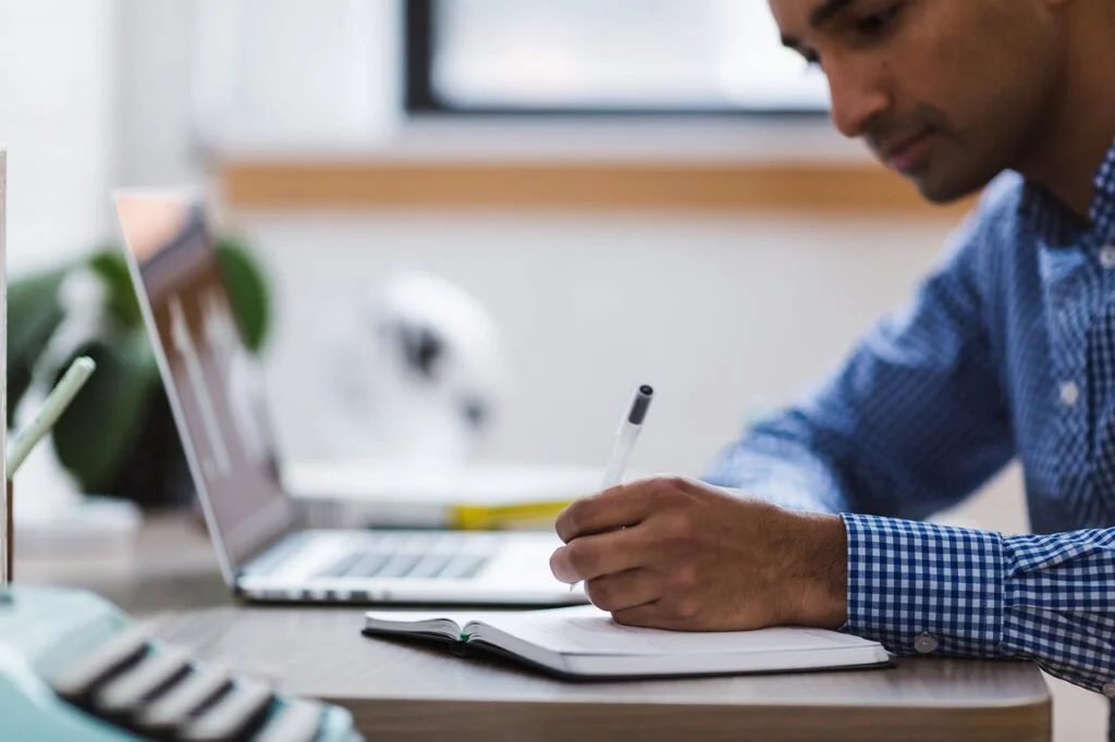 man writing on a pad taking ownership in his job.