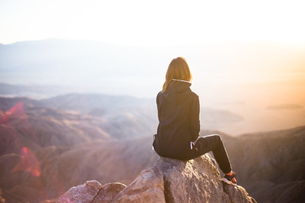 a woman sitting on a mountain thinking about the keys to success in life.