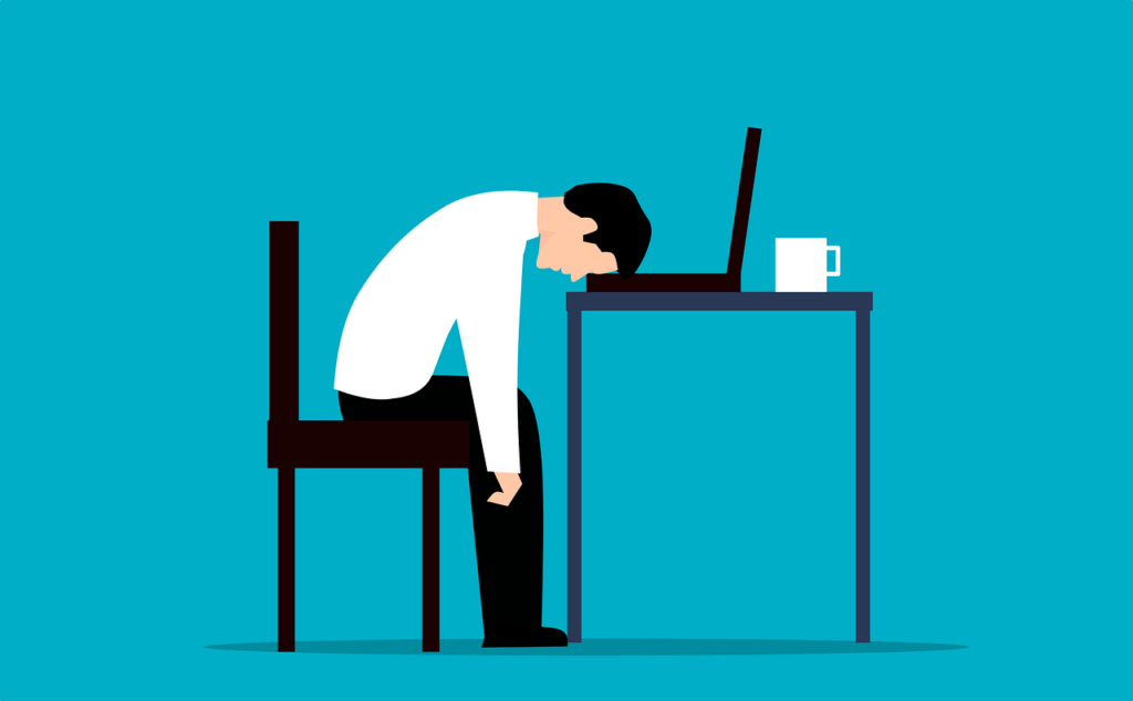 a man with his head on his desk exhausted from dealing with challenging employee types.